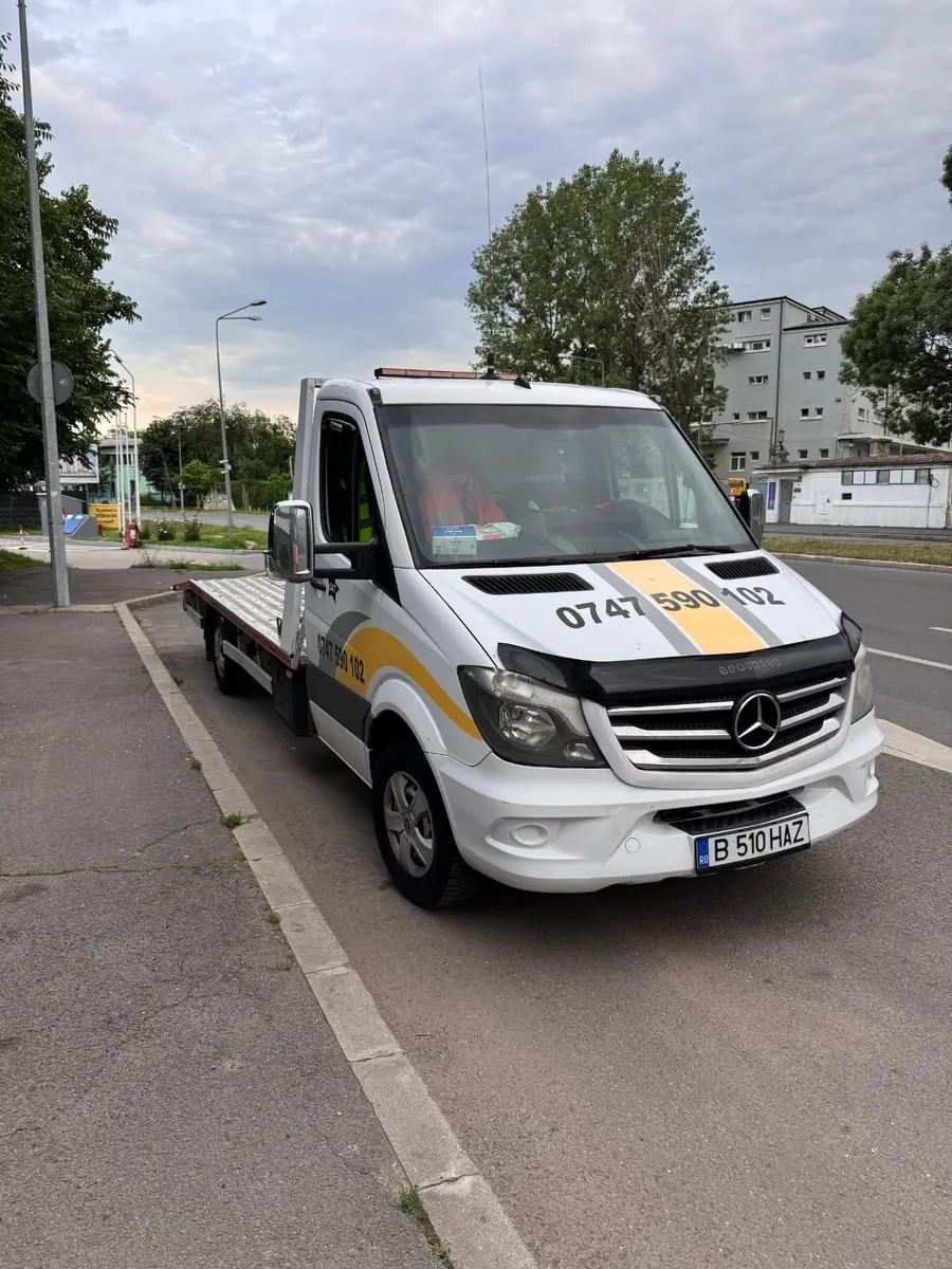 Platforma albă Mercedes Sprinter fotografiată frontal pe o stradă, fără vehicul încărcat
